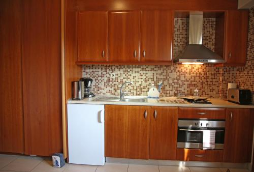 a kitchen with wooden cabinets and a white refrigerator at Sitia Bay in Sitia