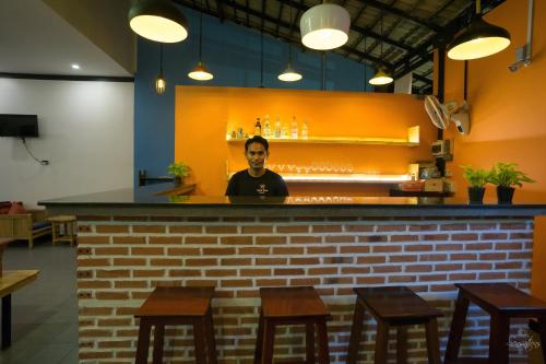 a man standing behind a bar in a restaurant at Noni Tree Hostel in Siem Reap