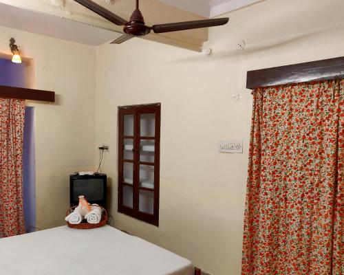 1 dormitorio con ventilador de techo y 1 cama con cortinas en Natraj Guest House, en Ajmer