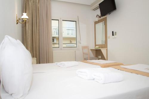 a bedroom with a white bed with towels on it at Hotel Astron in Mirina