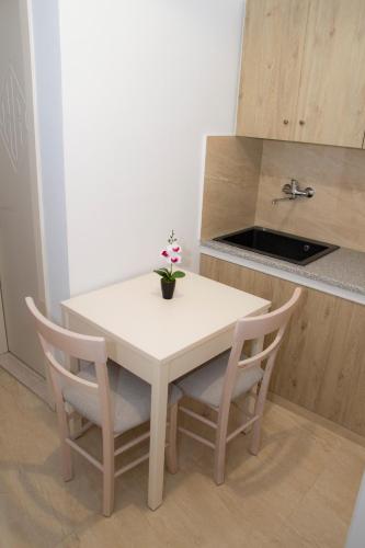 a white table with two chairs and a vase with flowers on it at Hotel Astron in Mirina