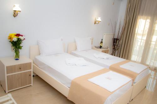 a bedroom with two beds and a vase of flowers at Hotel Astron in Mirina