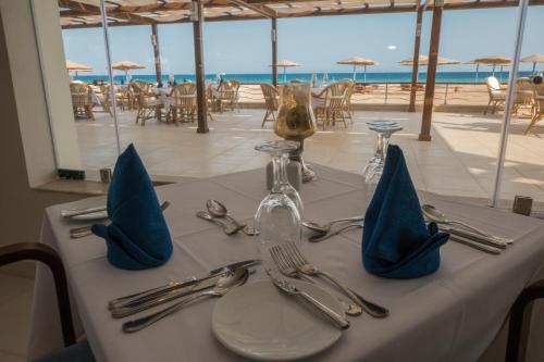 a table with silverware and napkins on top of a table with the beach at Shams Lodge in Hurghada