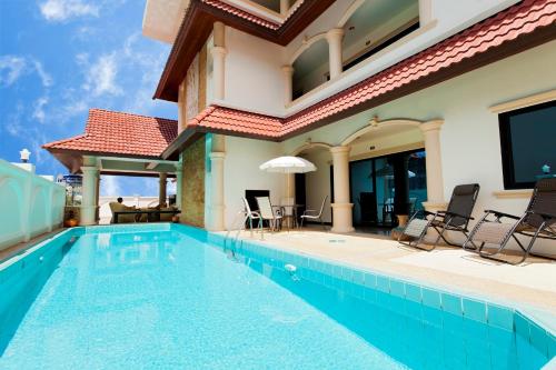 a swimming pool with chairs and a house at Royal Prince Residence in Patong Beach