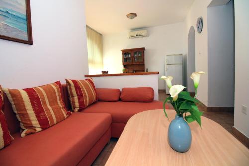 a living room with a red couch and a vase on a table at Apartments Maria in Tisno