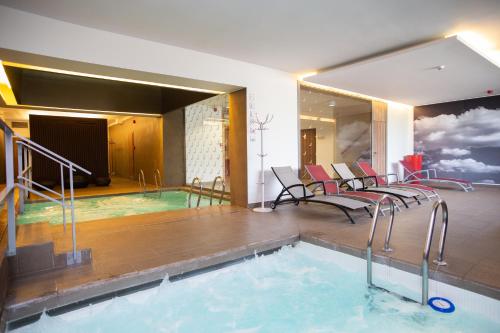 a room with a swimming pool with chairs and a swimming pool at Laterum Economy in Pécs