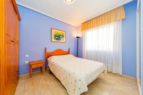 a bedroom with a bed and a blue wall at ALEGRIA ID118 in Torrevieja