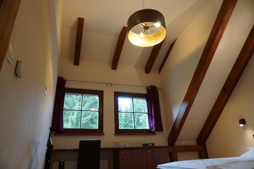 a bedroom with a ceiling fan and a window at Jezírko lesní restaurant & penzion in Jáchymov