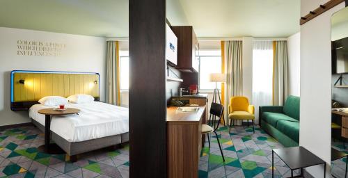 Habitación de hotel con cama y sofá verde en Park Inn By Radisson Hasselt en Hasselt