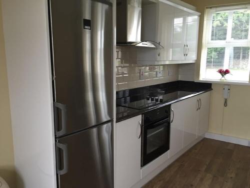 uma cozinha com um frigorífico de aço inoxidável e armários brancos em Curraghchase Cottage em Kilcornan