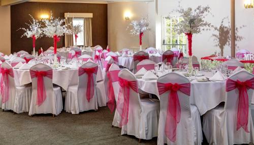 a room filled with tables with white chairs with bows at Best Western Thurrock Hotel in Grays Thurrock