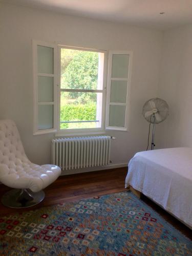une chambre avec un lit, une chaise et une fenêtre dans l'établissement Les Amarines, à Saint-Rémy-de-Provence