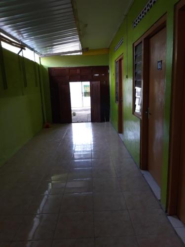 un corridoio vuoto con pareti verdi e una porta di Janti Transit Room Syariah a Yogyakarta