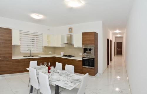 a dining room with a white table and white chairs at Lorenza Letting Apartment in Marsaxlokk
