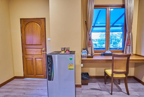 a kitchen with a refrigerator and a table and a window at Mina Garden Villa Resort in Chiang Mai