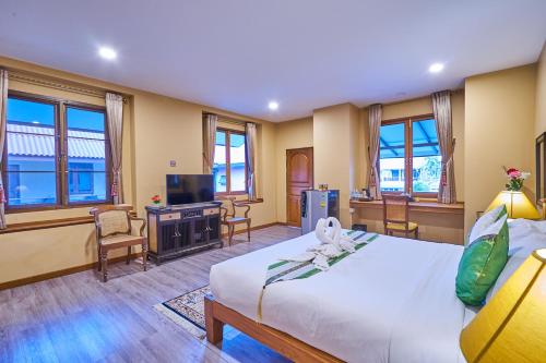 a hotel room with a bed and a television at Mina Garden Villa Resort in Chiang Mai