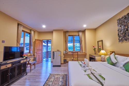 a living room with a white couch and a tv at Mina Garden Villa Resort in Chiang Mai
