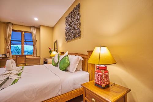a bedroom with a bed and a lamp on a table at Mina Garden Villa Resort in Chiang Mai