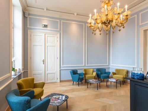 a waiting room with blue chairs and a chandelier at Hotel Kronacker in Tienen