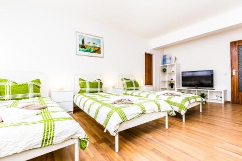 ein Zimmer mit drei Betten und einem Flachbildfernseher in der Unterkunft Workers Apartment am Wiener Platz in Köln