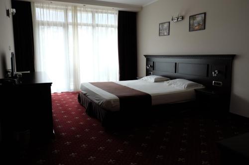a bedroom with a bed and a large window at Hotel Dragalevtsi in Sofia
