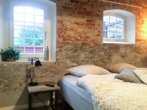 a bedroom with two beds and a brick wall at Hos Mette in Børkop