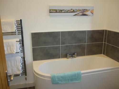 a bathroom with a bath tub with a picture on the wall at The Barn At Collacott in North Petherwin