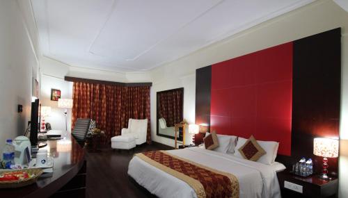 a bedroom with a large bed and a red wall at The South Park Hotel in Trivandrum