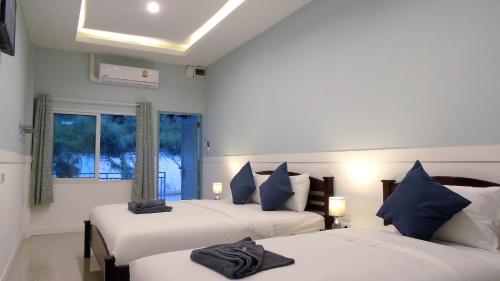 a bedroom with two beds with blue pillows and a window at Blue Moon Samed in Ko Samed