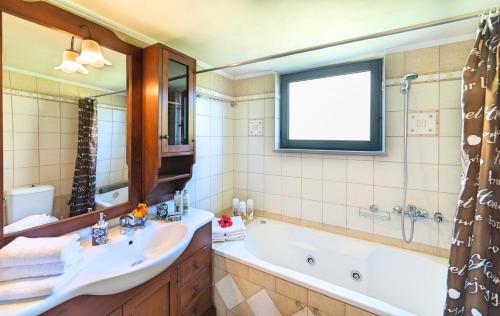 y baño con bañera, lavabo y espejo. en Sentido Villas en Arménoi