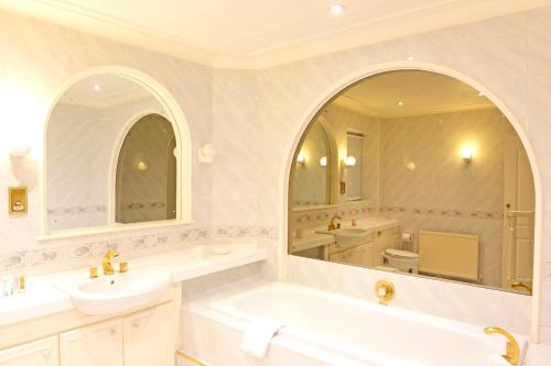 uma casa de banho com uma banheira, um lavatório e um espelho. em Fairways em Eastbourne