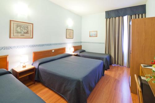 a hotel room with two beds and a television at Hotel Terminus & Plaza in Pisa