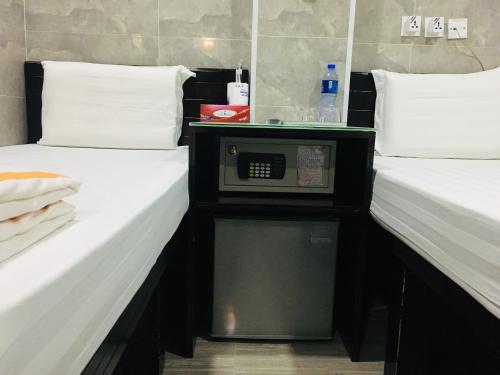 two beds in a hotel room with a microwave between them at Victoria Inn in Hong Kong