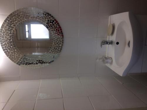 baño con espejo circular y urinario en Romilly Beach Apartment, en Strand