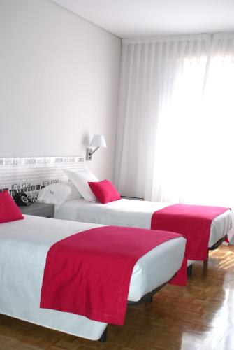 a hotel room with three beds with red sheets at Anaco in Madrid