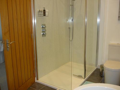 a shower with a glass door in a bathroom at The Barn At Collacott in North Petherwin