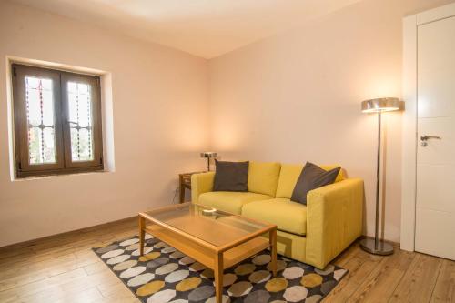 a living room with a yellow couch and a table at Hotel Los Cigarrales in Toledo