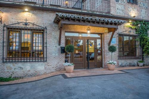 a brick building with a front door with potted plants at Hotel Los Cigarrales in Toledo