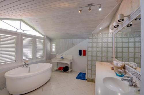 a white bathroom with a tub and a sink at Tantalus in Bridgetown