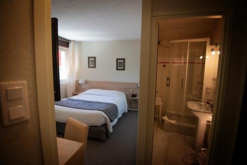 a bedroom with a bed and a bathroom with a sink at Hotel Restaurant Saint-Benoit in Gueugnon