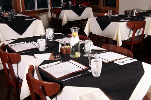 a group of tables with white clothed tables in a restaurant at Manoir D'Orsennens in Lac-Mégantic