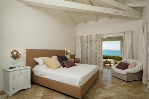 Un dormitorio con una cama y una silla y una ventana. en S'Abba seafront apartments - Your House in Sardinia, en Golfo Aranci