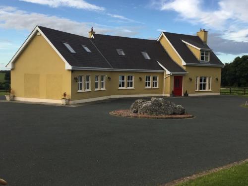 uma grande casa amarela com uma grande entrada em Curraghchase Cottage em Kilcornan