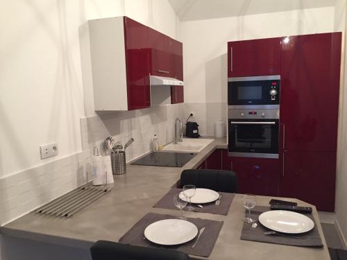 a kitchen with red cabinets and a table with two white plates at Studio Indépendant - Quartier Résidentiel in Marseille