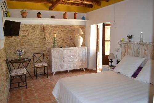 a bedroom with a bed and a stone wall at Casa Can Coves in Santa Gertrudis de Fruitera