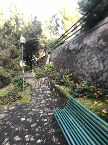 a green park bench sitting next to a stone wall at Appartamento del Golf - Secured Parking - in Rapallo