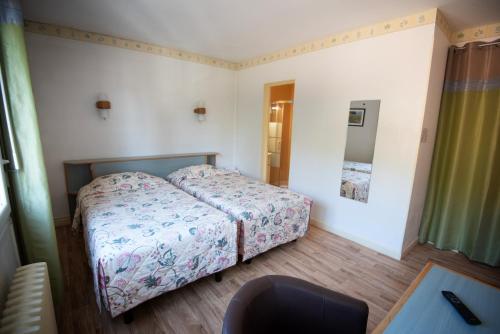 a small bedroom with a bed and a mirror at Hotel Restaurant Saint-Benoit in Gueugnon