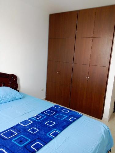 a bedroom with a blue bed and a wooden cabinet at HOSPEDAJE-FLORIDABLANCA-SANTANDER in Floridablanca