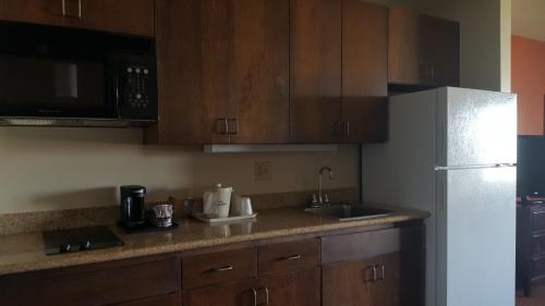 a kitchen with wooden cabinets and a white refrigerator at AmericInn by Wyndham Muscatine in Muscatine