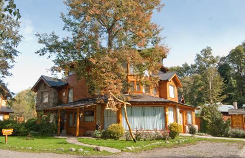 a house with a tree in front of it at Apart Hotel del Pellin in San Martín de los Andes